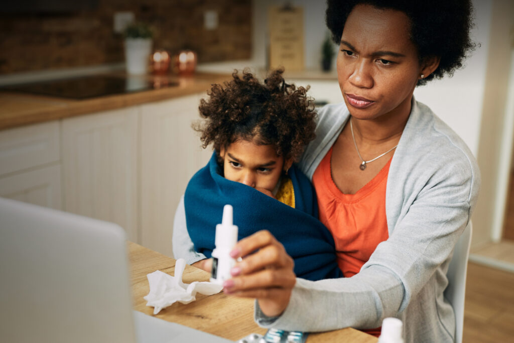 Mom and son showing medication to a doctor through telemedicine on a computer.